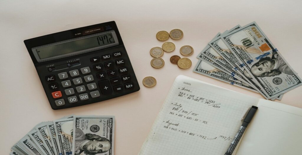 Smart financial planning setup with calculator, coins, currency notes, and notebook representing budgeting, high-yield savings growth, and secure money management.